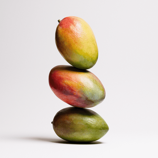 Three mangoes stacked on top of each other against a white background